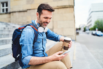 Tourist sitting out in the city having coffee and using smartphone