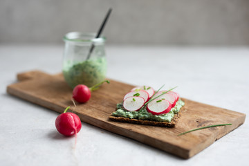 Jar with radish leaves, mint and ricotta dip, crackers topped with ricotta dip and fresh radish...