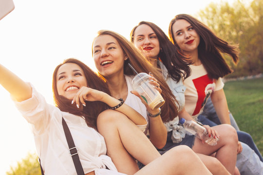 Group of young happy carefree girls friends making selfie on summer city street, sunset time background
