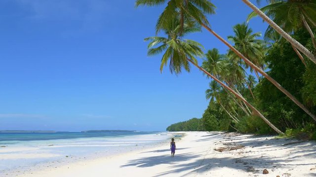 Woman sunbathing walking on white sand beach turquoise water tropical coastline Wab Kei Islands Indonesia paradise travel destination sunny hot day