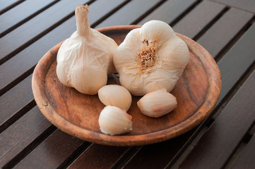 Closeup of garlics on antique wooden board.