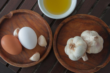 Closeup of garlic on a board of old wood, olive oil and eggs.