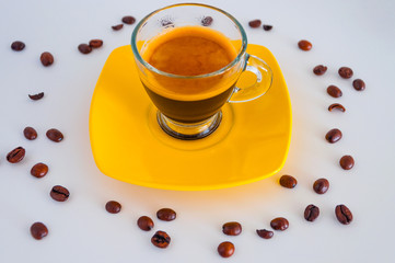 Close up of cup and coffee beans on yellow platter.