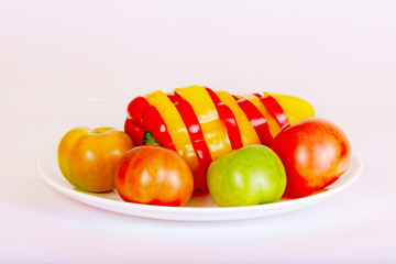 Bulgarian pepper and tomatoes lie on a white plate.