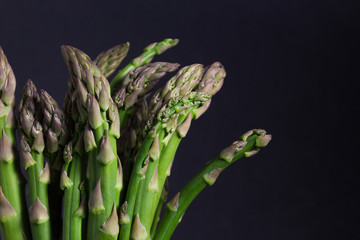 Vibrant close up of fresh asparagus on black background, horizontal