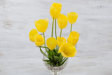 yellow tulips, a bouquet in a vase on a wooden background