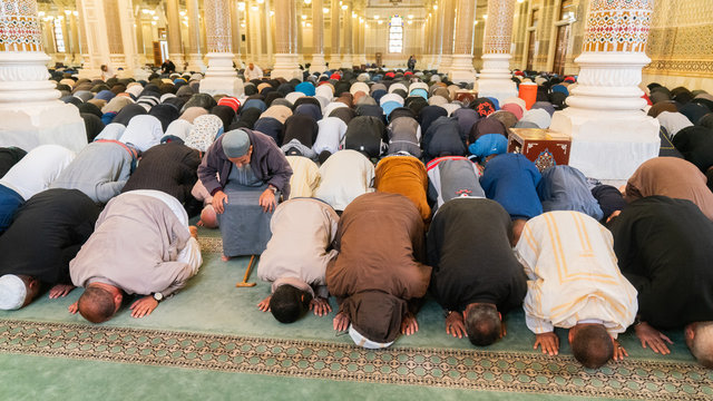 Muslim men bowing, kneeling and praying inside of a big mosque in Constantine, Algeria