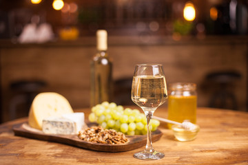 Naklejka na ściany i meble Glass of white wine ,cheese and grapes on old wooden table