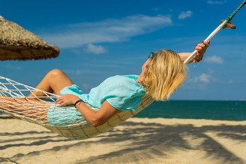 Naklejka premium Woman sitting in hammock on the beach.