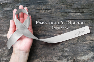 Silver color ribbon on hand support (isolated with clipping path) for Parkinson's disease awareness and Brain cancer tumor illness
