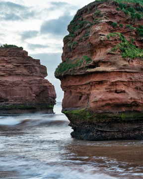 Stunning sunrise landscape image of Ladram Bay beach in Devon England with beautiful rock stacks on beach