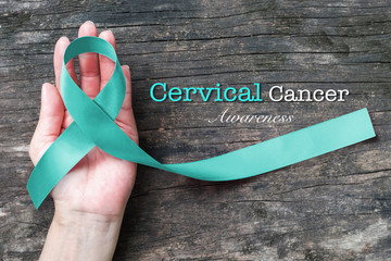 Cervical Cancer awareness with Teal ribbon symbolic bow color on woman helping hand support on old...