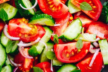 Fresh summer salad bowl with tomatoes, cucumbers, red onions, basil closeup.