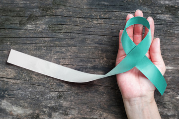 Teal and white ribbon for Cervical Cancer awareness campaign concept symbolic bow color on woman...