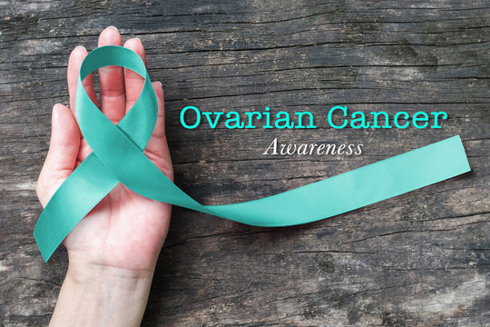 Teal ribbon on helping hand support for raising awareness on Ovarian Cancer illness in women's health