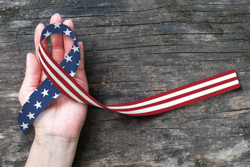 American flag pattern awareness ribbon on people's hand (isolated with clipping path) for USA...