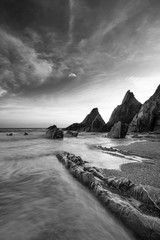 Superbe image de paysage au coucher du soleil de la plage de Westcombe dans le Devon en Angleterre avec des rochers déchiquetés sur la plage et de superbes formations nuageuses