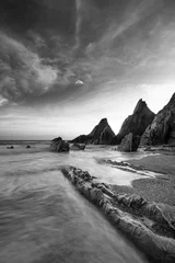 Papier Peint photo Lavable Noir et blanc Superbe image de paysage au coucher du soleil de la plage de Westcombe dans le Devon en Angleterre avec des rochers déchiquetés sur la plage et de superbes formations nuageuses