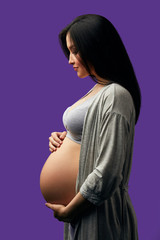 Profile studio shot of expectant mother touching belly, listens how her unborn child moving in...