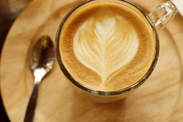 Top view of coffee cup latte art put on wooden saucer.