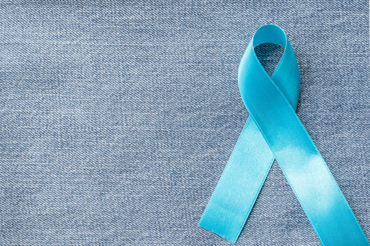 Blue ribbon symbolic of prostate cancer awareness campaign and men's health in November month on Jeans denim