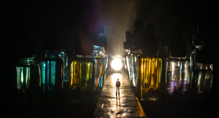 Silhouette of a man standing in the middle of the road on a misty night with giant glass bottles...