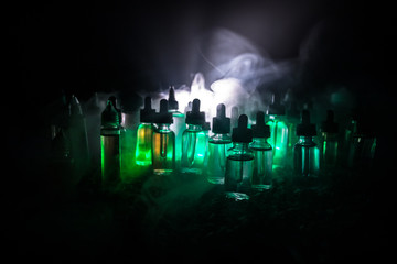 Vape concept. Smoke clouds and vape liquid bottles on dark background. Light effects. Useful as...