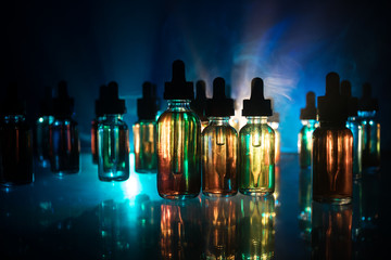 Vape concept. Smoke clouds and vape liquid bottles on dark background. Light effects. Useful as...