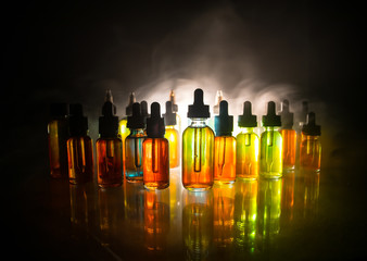 Vape concept. Smoke clouds and vape liquid bottles on dark background. Light effects. Useful as background or electronic cigarette advertisement.