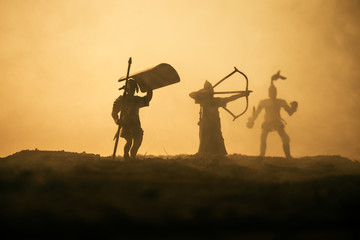 Medieval battle scene with cavalry and infantry. Silhouettes of figures as separate objects, fight between warriors on sunset foggy background.