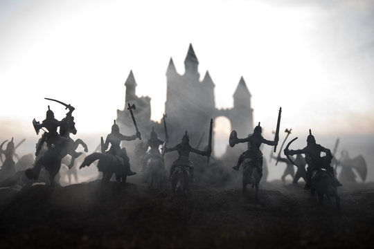 Medieval battle scene with cavalry and infantry. Silhouettes of figures as separate objects, fight between warriors on sunset foggy background.