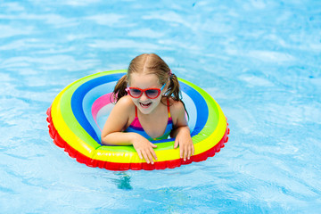 Child in swimming pool on toy ring. Kids swim.