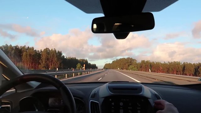 road view through car windshield, dashboard and steering wheel with driver's hands, concept of traveling by car
