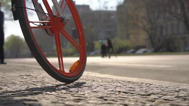 Bicycle wheel with orange spokes in front of rooler skating marathon with refocus (compound, 1080p, 50fps)