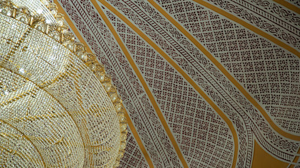 Ceiling of mosque covered in Islamic patterns and a big chandelier