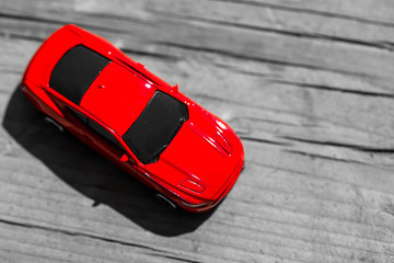 Red toy car on grey wooden background with space for lettering or design. Close up. Top view.