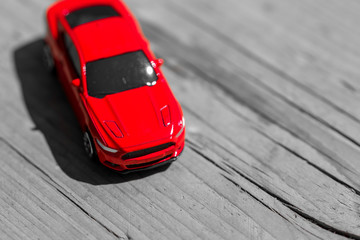Red toy car on grey wooden background with space for lettering or design. Close up.