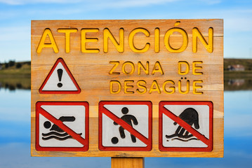 Sign in Spanish stating Attention! Drainage area. Banned bathing, playing, can not touch the water....