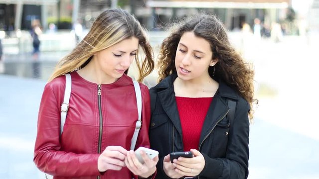 Two female friends looking at a smartphone and smiling