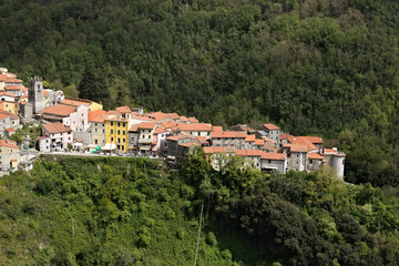 Fototapeta na wymiar View of the town of Colonnata, famous for the production of lard. The walls of the houses in stone and white Carrara marble. Woods background. Northern Tuscany. Colonnata, Carrara, Italy.