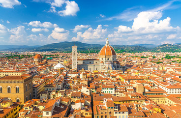 Fototapeta premium Top aerial panoramic view of Florence city with Duomo Cattedrale di Santa Maria del Fiore cathedral, buildings houses with orange red tiled roofs and hills range, blue sky white clouds, Tuscany, Italy