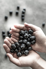 Organic Blueberries in Female Hands on Dark Background. Antioxidant Superfood Healthy Eating Concept.