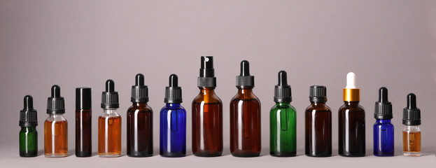 Cosmetic bottles of essential oils on color background