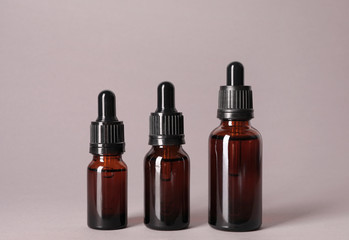 Cosmetic bottles of essential oils on color background