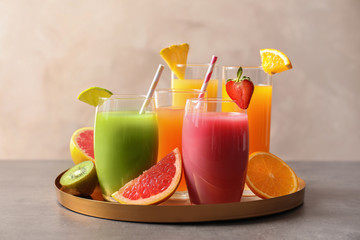 Tray with glasses of different juices and fresh fruits on table