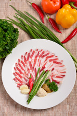 Plate with meat cutting, strips of bacon and sliced lard, sauce, greens. The concept of Russian Ukrainian restaurant. Flat lay top view.