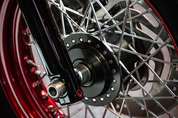 Fototapeta na wymiar Detail of the black wheel of a customized motorcycle chromed with red and silver wheels