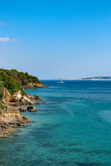 Obraz premium View from a beach during summer, located on a beautiful island of Rab on the Adriatic coast in the heart of Mediterranean sea. Surrounded by the crystal clear turquoise sea and blue sky.
