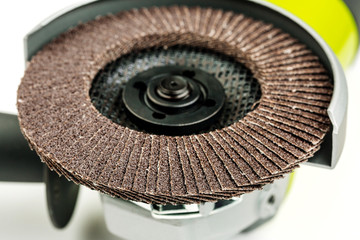 Angle grinder with abrasive disk on white background