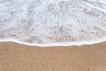 soft wave with foam on a sandy beach, with copy space, summer